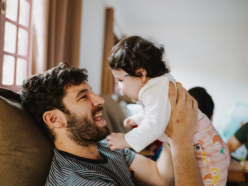 dad and baby daughter playing on couch